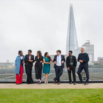 Photo of colleagues standing on rooftop in city
